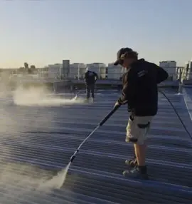 man using pressure washer to clean the roof