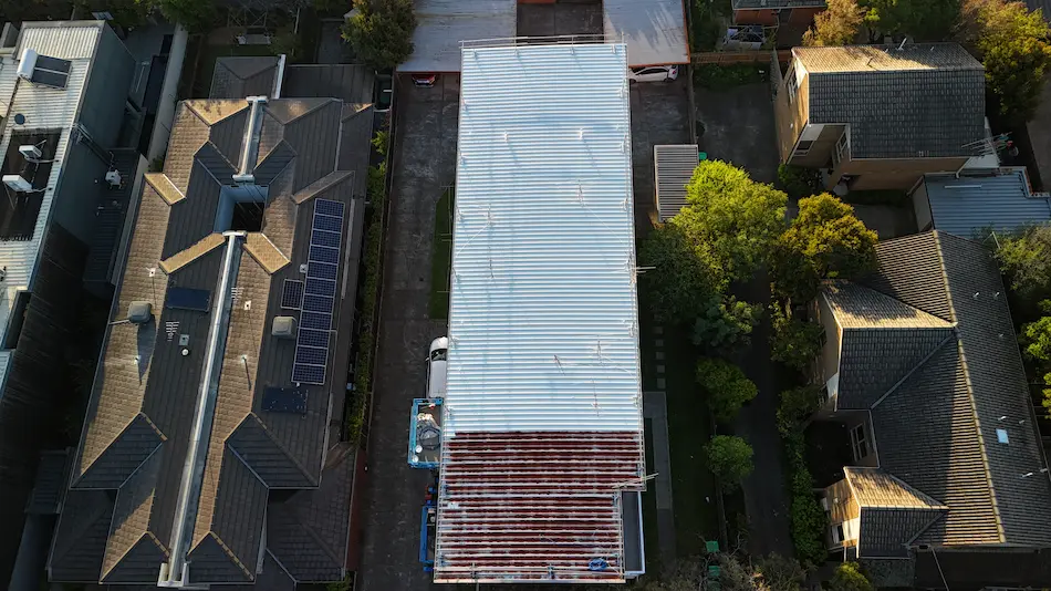 Commercial painters using spray gun to apply Noxyde system on metal roof in Peel St Kew.