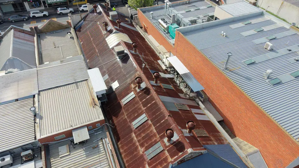 Angled aerial photo of Fairfield commercial roof with severe rust visible along sheet laps