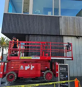 Image of a scissor lift carrying a man for roof painting