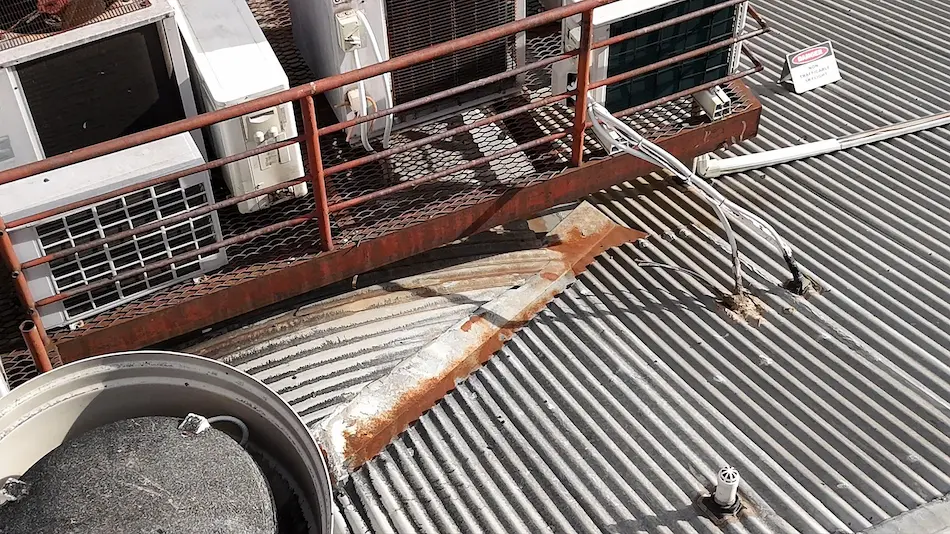 Rust-affected gutter and roof penetrations on building before membrane application